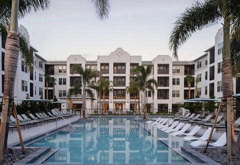 A large white hotel with a pool in front.