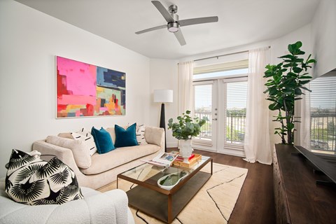 A living room with a white couch, a coffee table, and a painting on the wall.