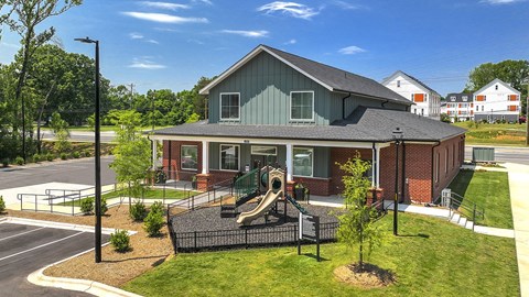 A playground with a slide is in front of a building.