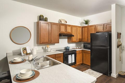 A kitchen with wooden cabinets and a black refrigerator.