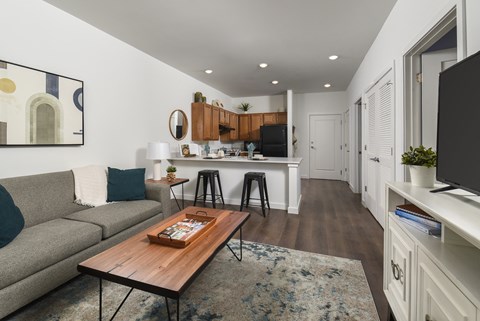 A modern living room with a grey couch, a wooden coffee table, and a painting on the wall.