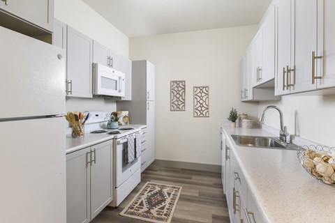 A kitchen with white cabinets and a rug on the floor.