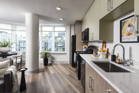 A modern kitchen with a black fridge and wooden floors.