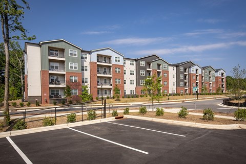 Apartment complex with a parking lot in front.