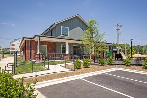 A building with a grey roof and a parking lot in front.