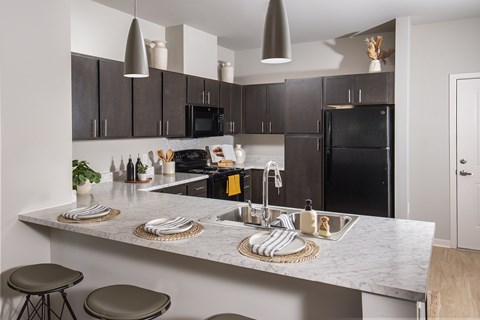 A kitchen with a black refrigerator and a marble countertop.