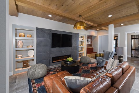 A modern living room with a brown leather couch and a fireplace.