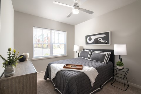 A bedroom with a bed, nightstand, and a plant.