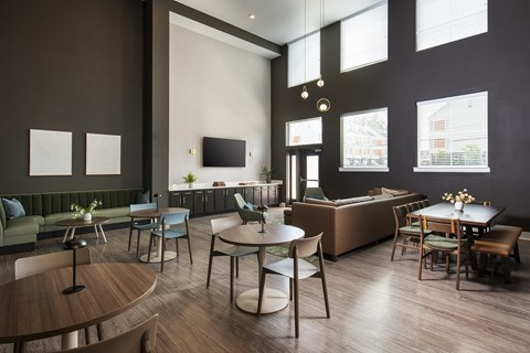 A modern living room with a green sofa, wooden chairs, and a television.