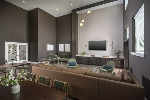 A living room with a brown couch and green chairs.
