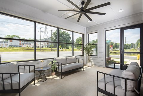 A sunny day in a room with a ceiling fan and a view of the street.