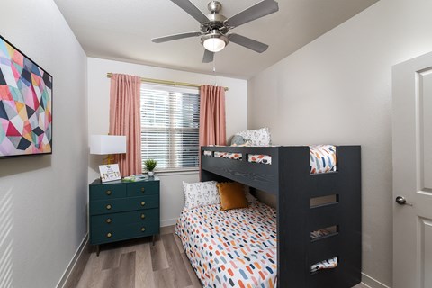 Bedroom featuring a large window, ceiling fan, wood-style flooring, and a functional layout with space for multiple sleeping arrangements.