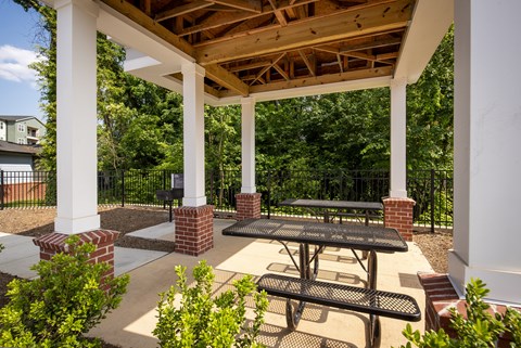 A white pillar and a black table are in the middle of a patio.