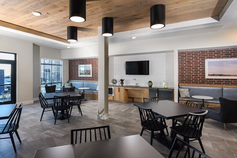 Resident clubhouse featuring dining tables, lounge seating, and a kitchenette for gatherings and community events.