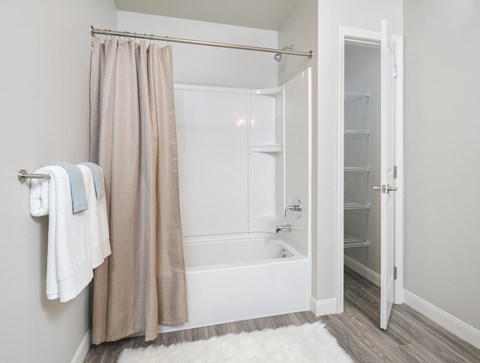 A white bathroom with a shower curtain and a white towel hanging on the wall.