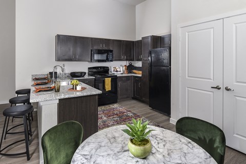 A kitchen with black cabinets and a marble countertop.