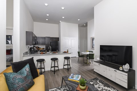 A modern living room with a yellow sofa and a black and white rug.