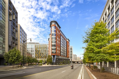 A street view of Emblem Apartments in the NOMA neighborhood of DC and a clear blue sky.