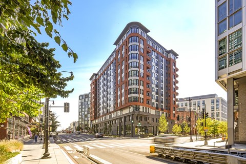A street view of a city with a large red building in the center.