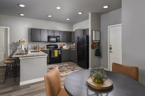 A modern kitchen with a black refrigerator and a dining table with chairs.