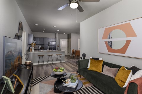 A living room with a green couch and a painting on the wall.