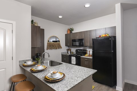 A kitchen with a black refrigerator and a counter with plates on it.