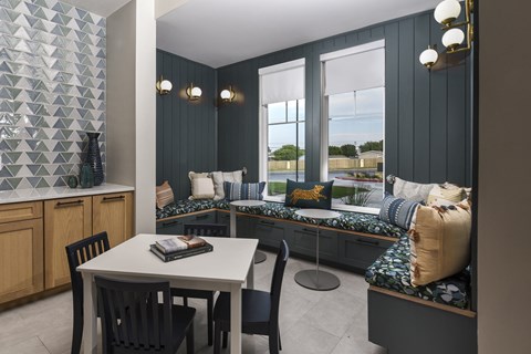 Dining nook with built-in bench seating, accent wall detailing, and a small table set near large windows.