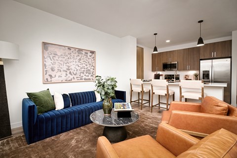 A living room with a blue couch and brown chairs.