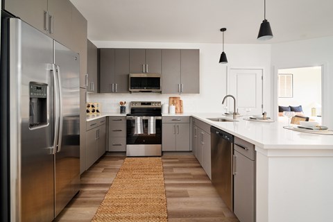 A modern kitchen with a refrigerator on the left and a sink on the right.