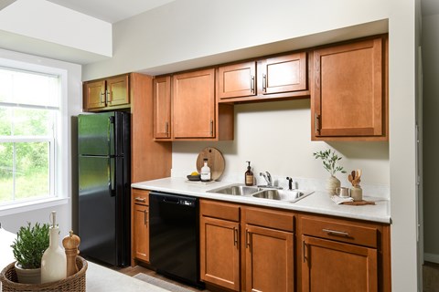 A kitchen with wooden cabinets and a black refrigerator.