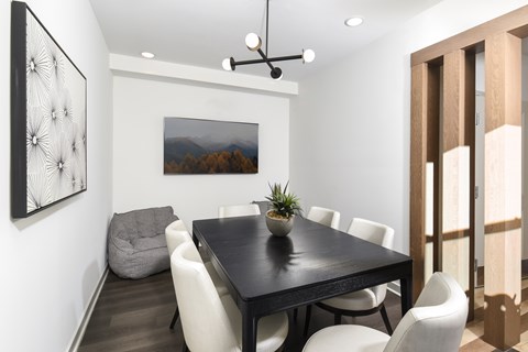 Stylish meeting space featuring a central table, upholstered chairs, and contemporary lighting with clean, modern finishes.