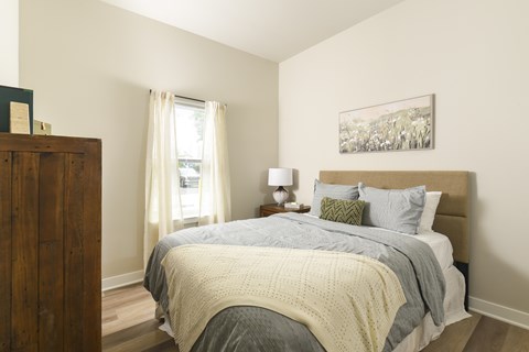 A bedroom with a bed covered in a grey and white comforter.