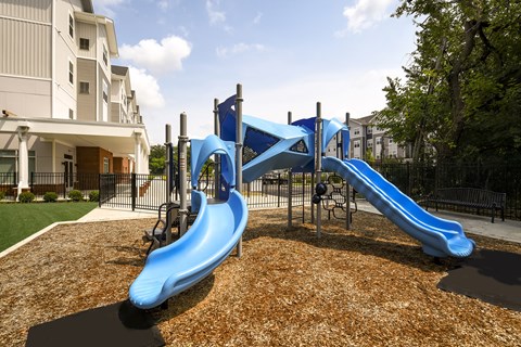 A playground with a blue slide and a brown surface.