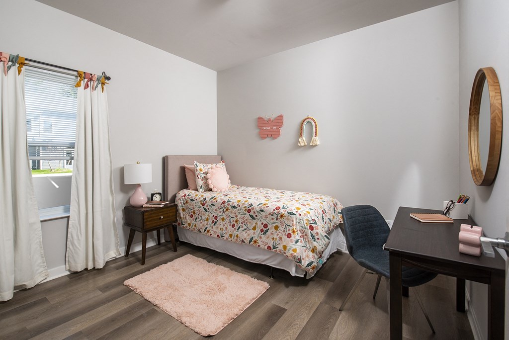 a bedroom with a bed and a desk and a window