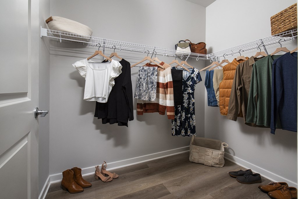 a closet with clothes hanging on a rack and shoes on the floor