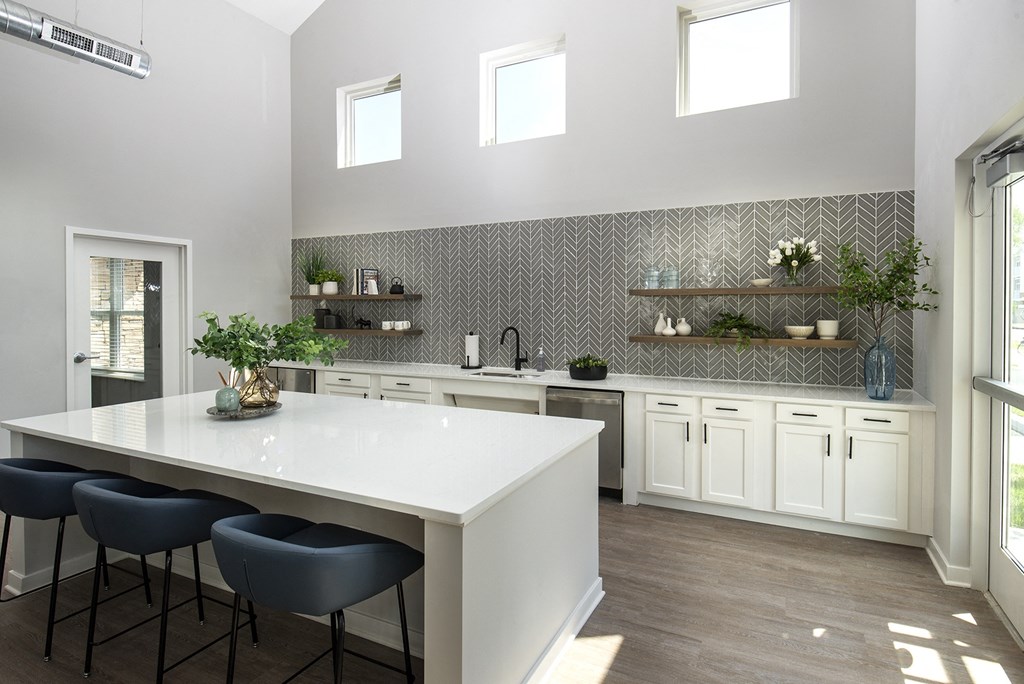 a large white kitchen with a white counter top and blue chairs