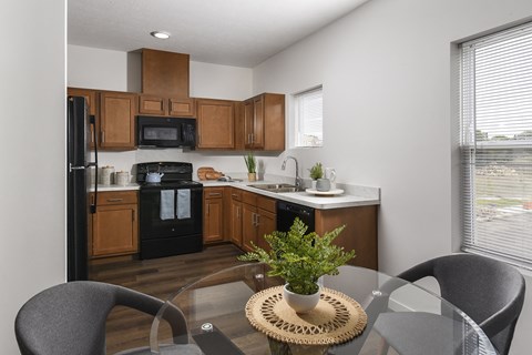 A kitchen with a black fridge and black oven with wooden cabinets.