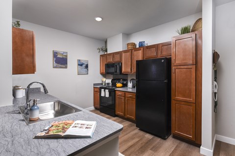 A kitchen with a black refrigerator and wooden cabinets.