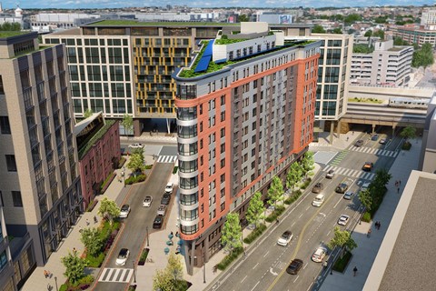 An aerial view of The Emblem modern apartment community with multi-story buildings, landscaped sidewalks, and walkable streets in a vibrant city setting.
