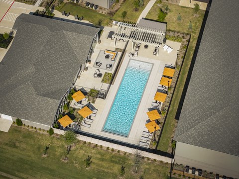 An aerial view of a pool surrounded by orange unbrellas and ample seating