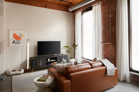 A living room with a brown leather couch and a flat screen TV.