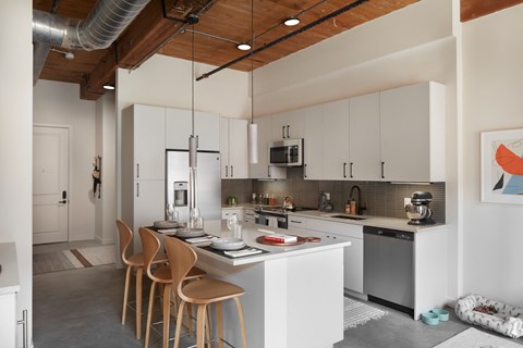 A modern kitchen with white cabinets and a wooden ceiling.