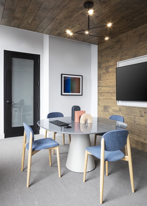 A modern dining room with a glass table and blue chairs.