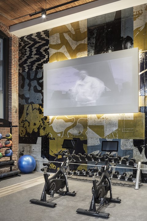A gym with a brick wall and a screen displaying a man.