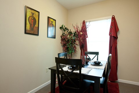 A dining room with a table set for two and a vase of flowers on the table.