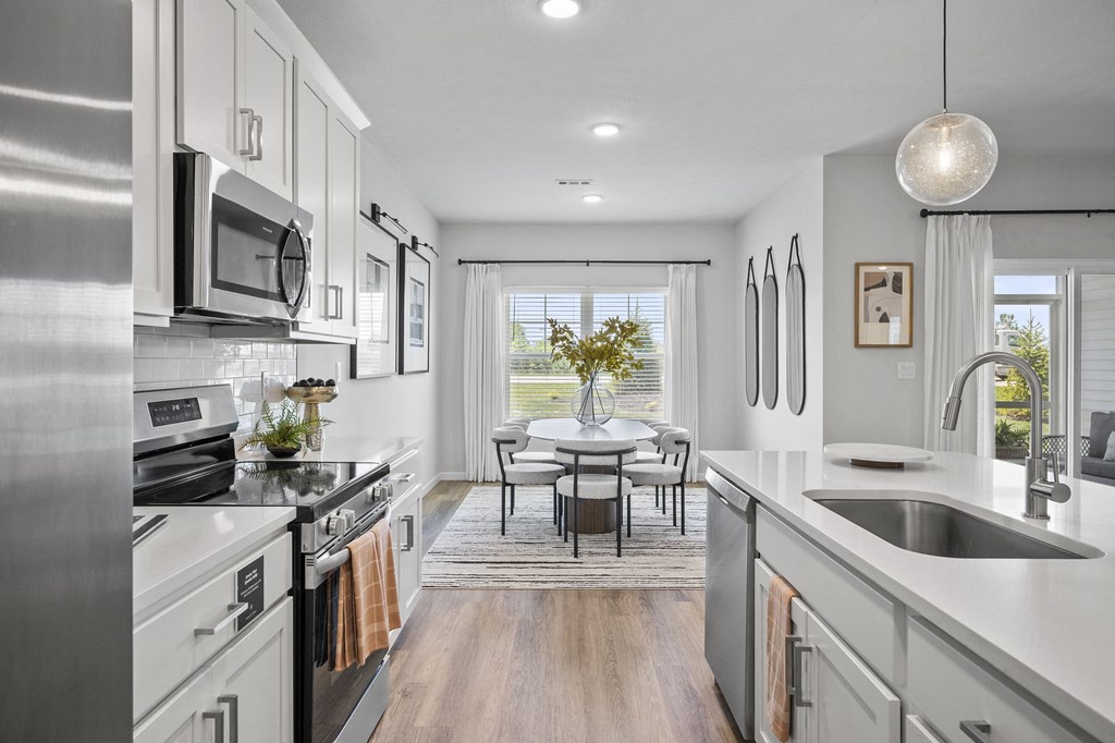 a kitchen with white cabinets and stainless steel appliances and a table with chairs