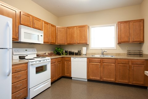 A kitchen with brown cabinets and white appliances.
