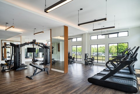 A gym with a variety of equipment including treadmills, weights, and exercise machines.