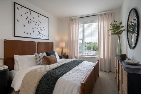 A bedroom with a large bed and a painting on the wall.