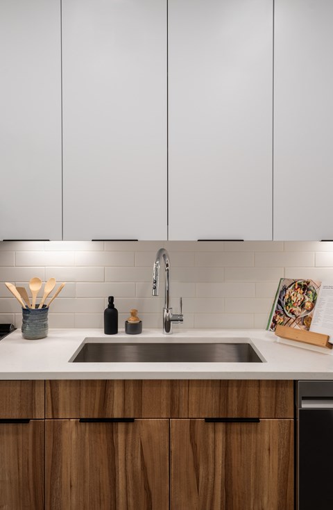 A kitchen with a sink and wooden cabinets.